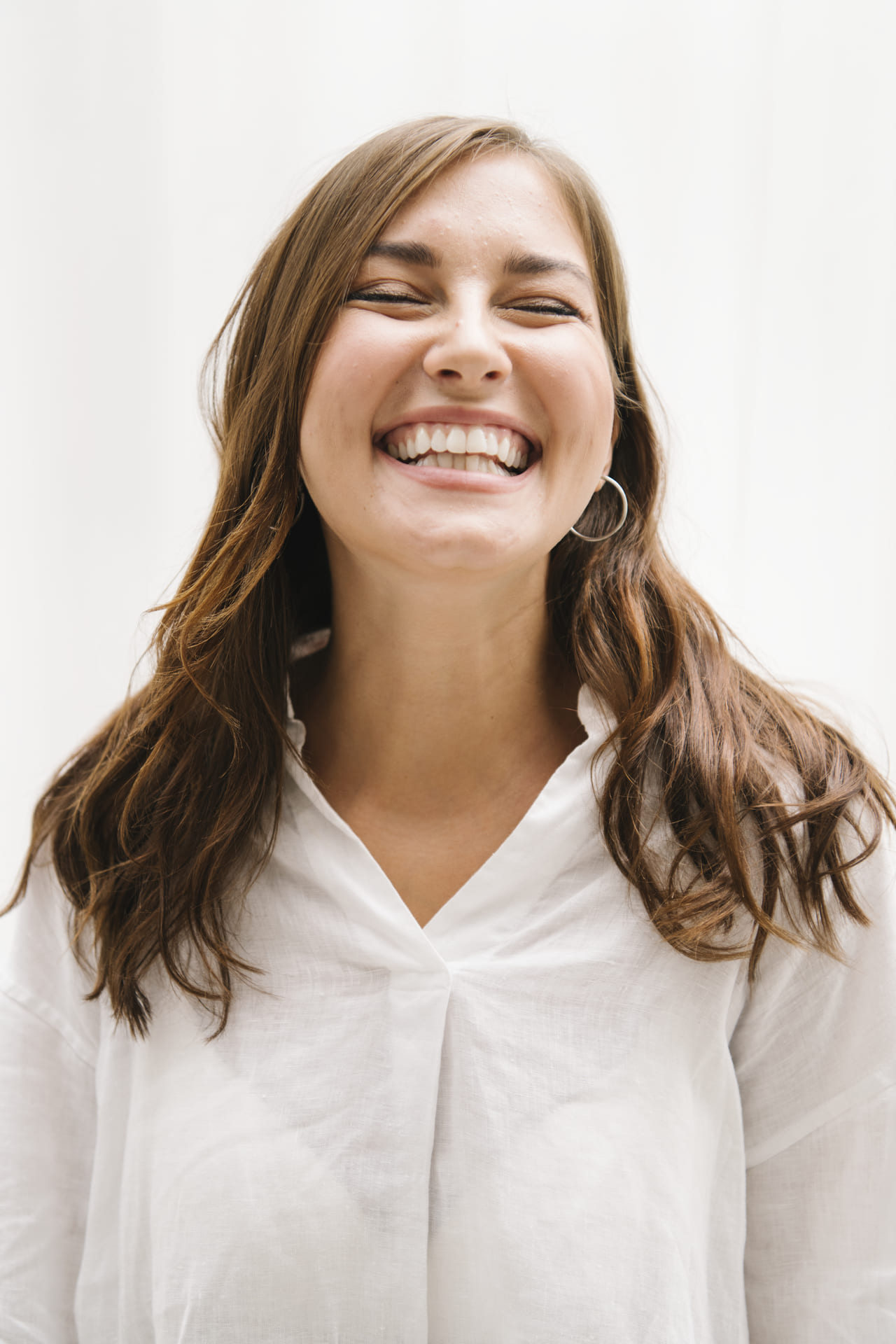 cheerful woman standing against a white wall 2025 02 10 13 46 49 utc